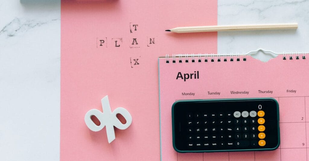 Flat lay of April calendar with calculator, pencil, and pink background for financial planning.